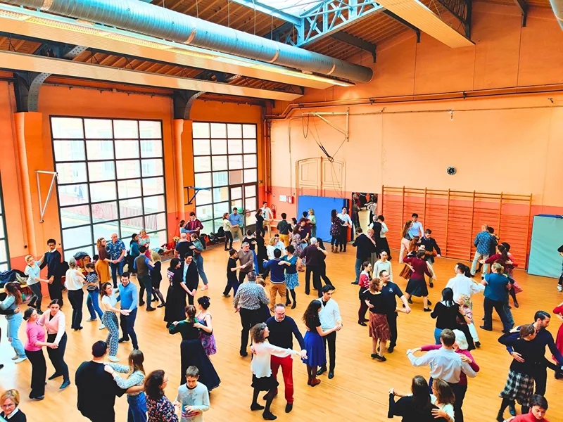 Des couples de danseurs pratiquent ensemble dans un gymnase pendant un cours de Carnet de Bals