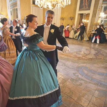 Un couple en robe verte et habit noir danse au Palazzo Gangi