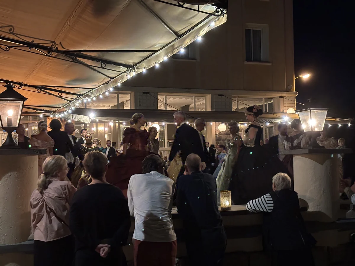 Participants et spectateurs installés sous la terrasse éclairée, face aux danseurs