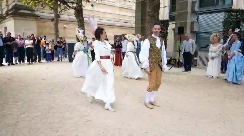 Danseuses en robes claires et danseur en habit doré lors d’une démonstration dans les jardins de l’Hôtel de Rohan