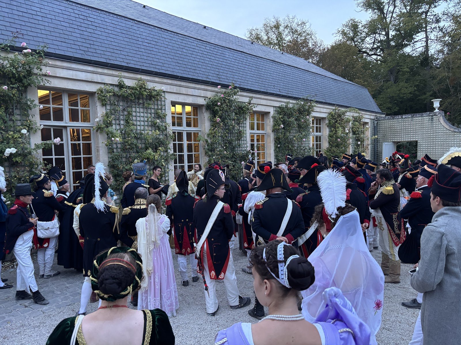 Reconstituteurs en uniformes militaires et participants en costumes Premier Empire réunis devant la dépendance de Chantilly pour le cocktail de bienvenue